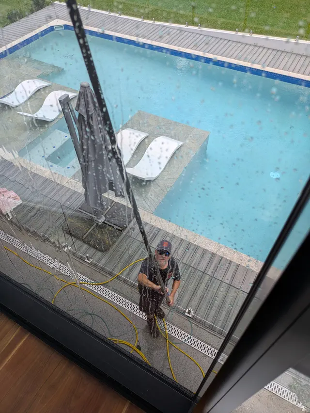 Wish You Were Clear technician reaching upper-storey glass with a water-fed pole