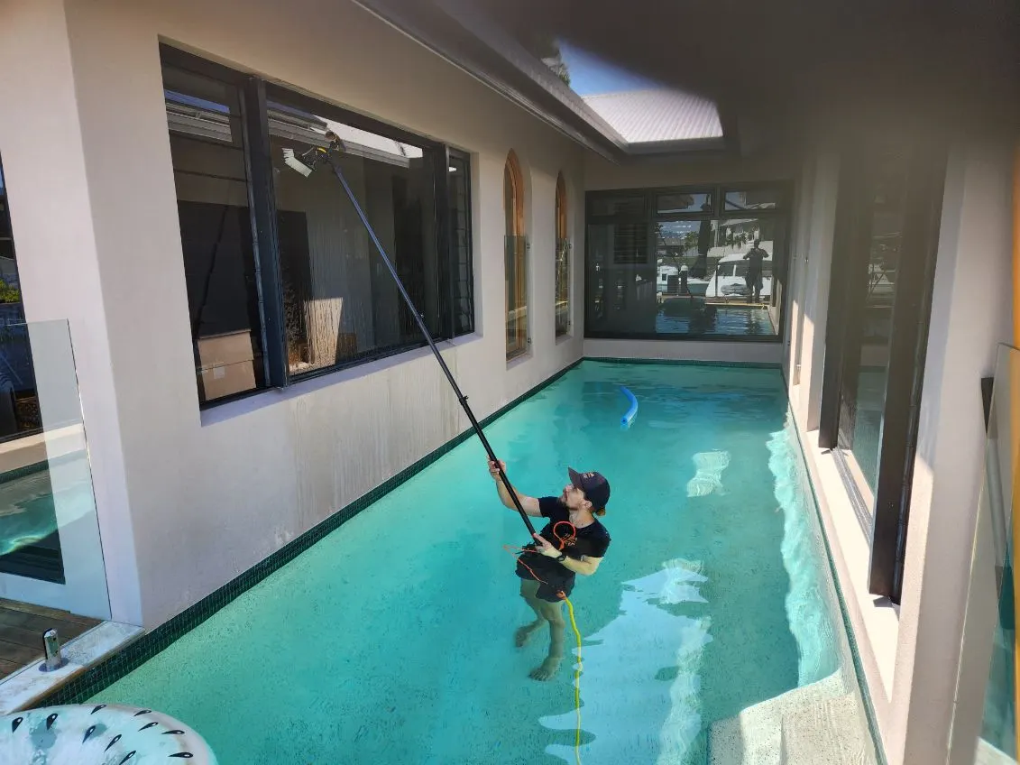 Water-fed pole cleaning windows beside a Cairns holiday rental pool