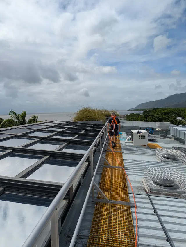 Technician cleaning upper-level windows of a multi-storey strata building with a pole system